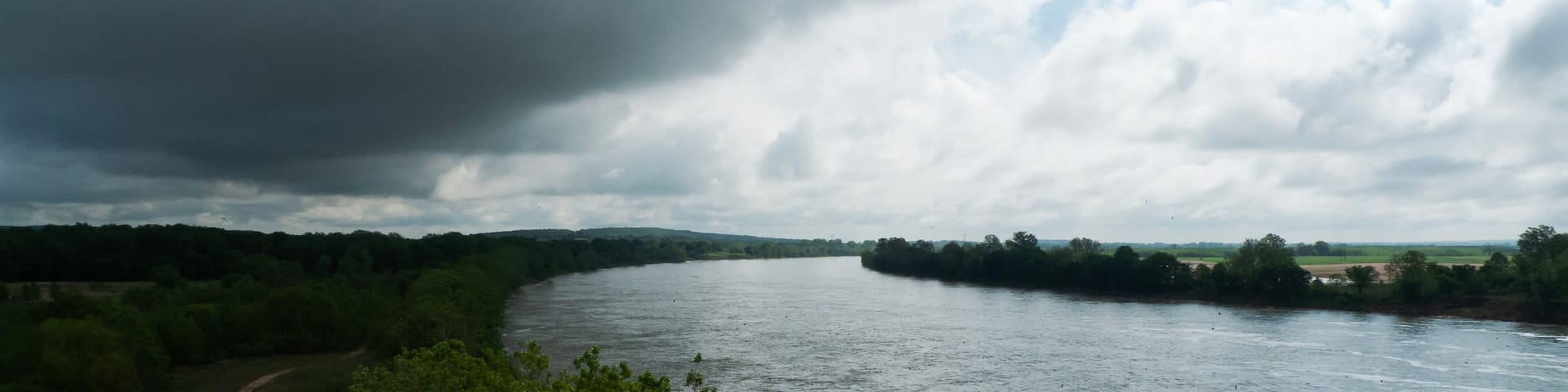 A river winding through a green landscape with a cloudy sky.