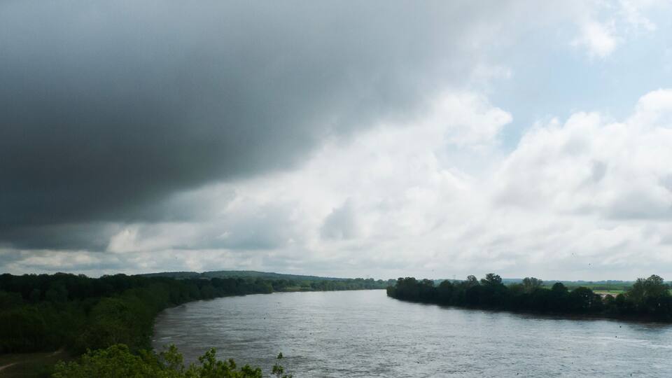 A river winding through a green landscape with a cloudy sky.