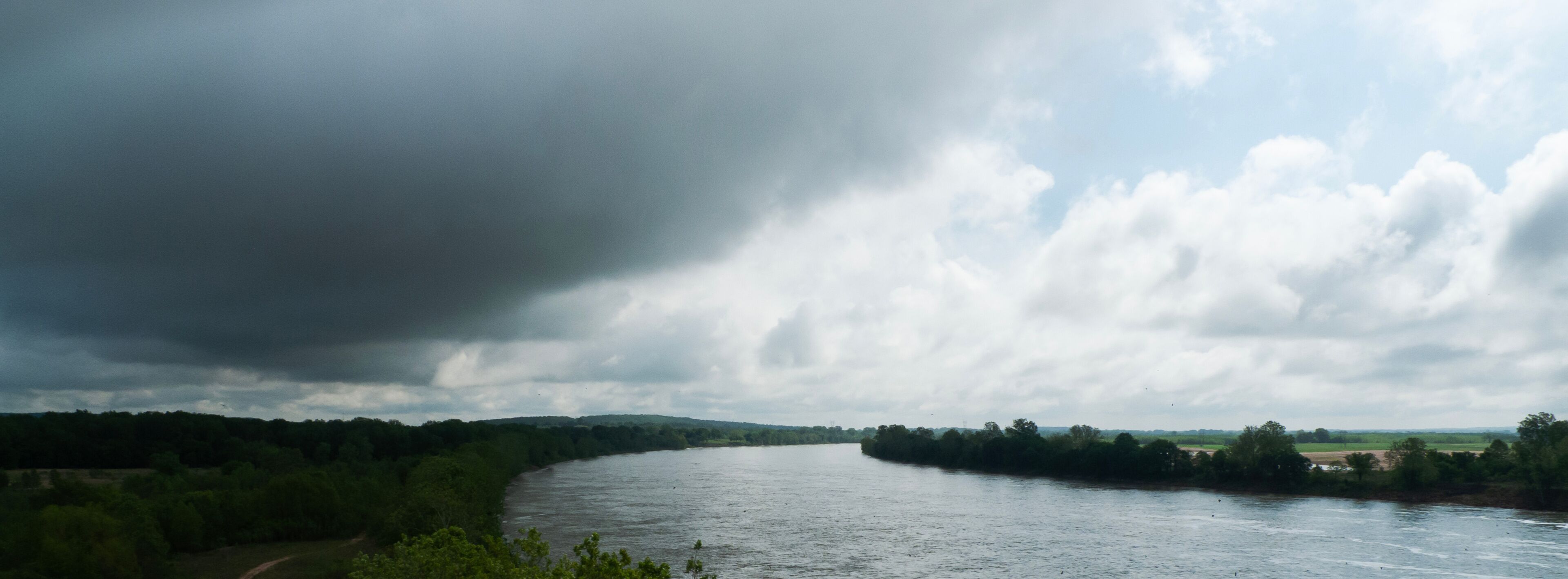 A river winding through a green landscape with a cloudy sky.