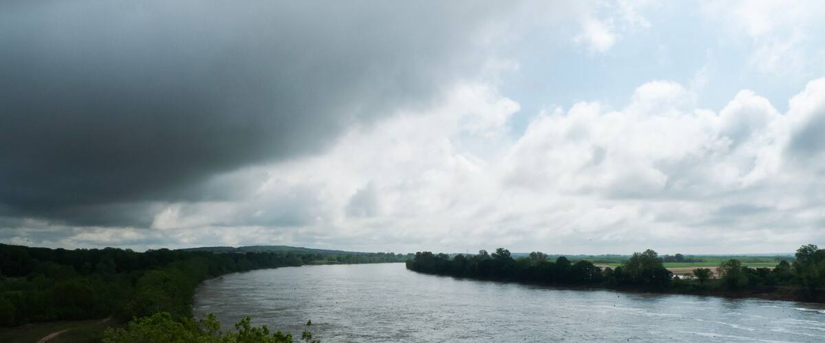 A river winding through a green landscape with a cloudy sky.