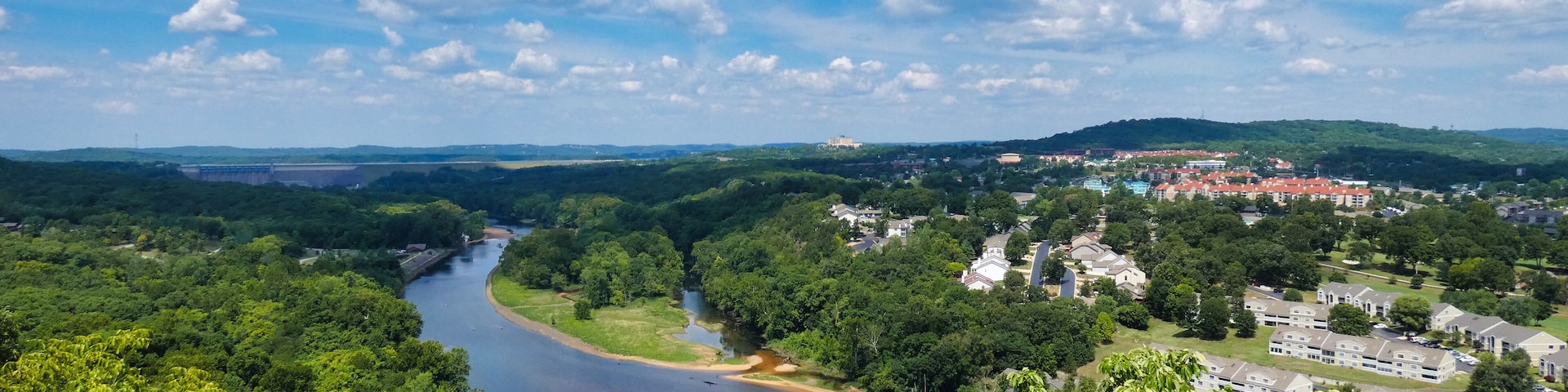 A river winding through a forested area with a town in the background.