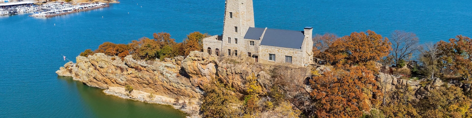 A stone castle on a rocky island surrounded by a lake.