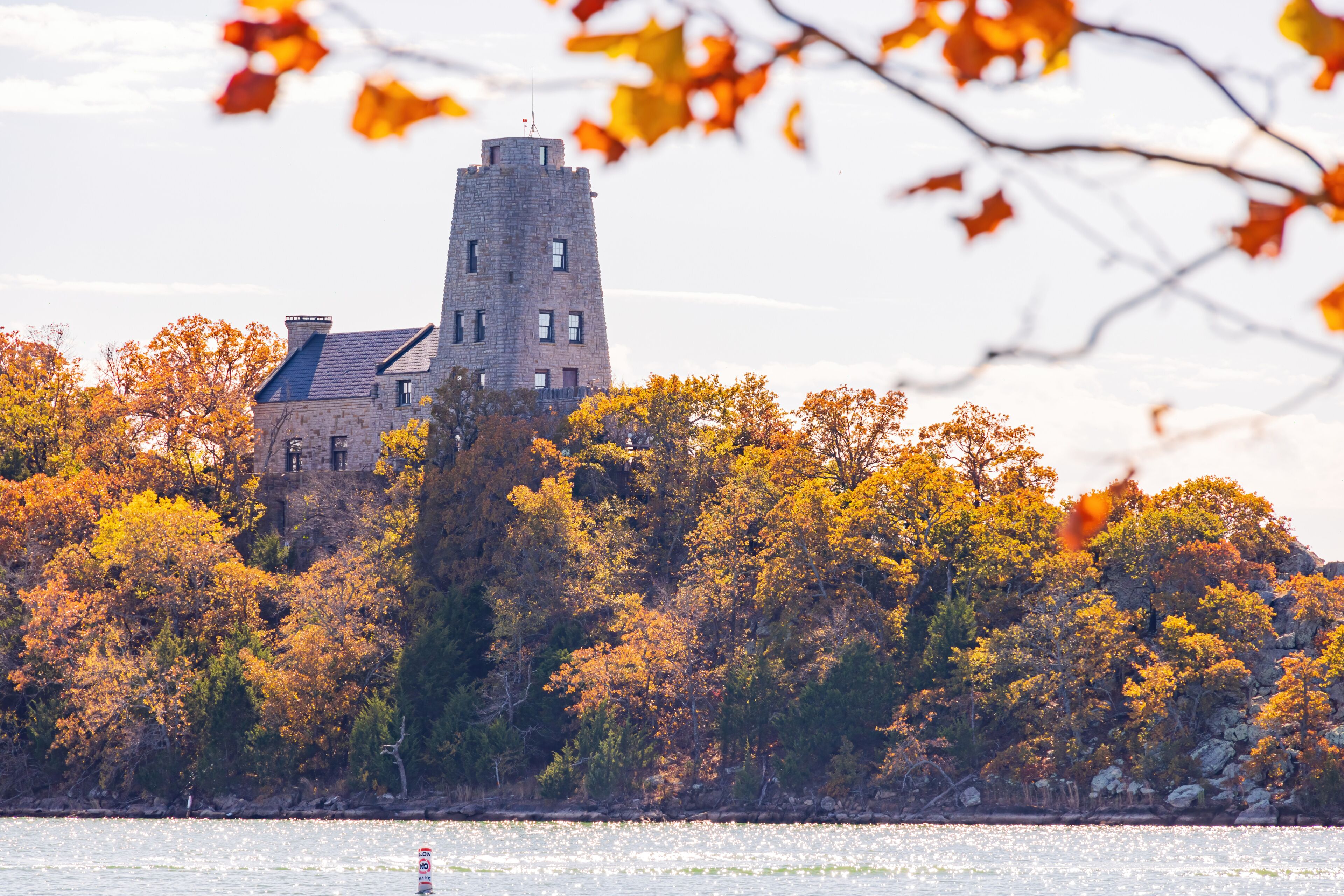 A castle surrounded by autumn trees and a body of water.