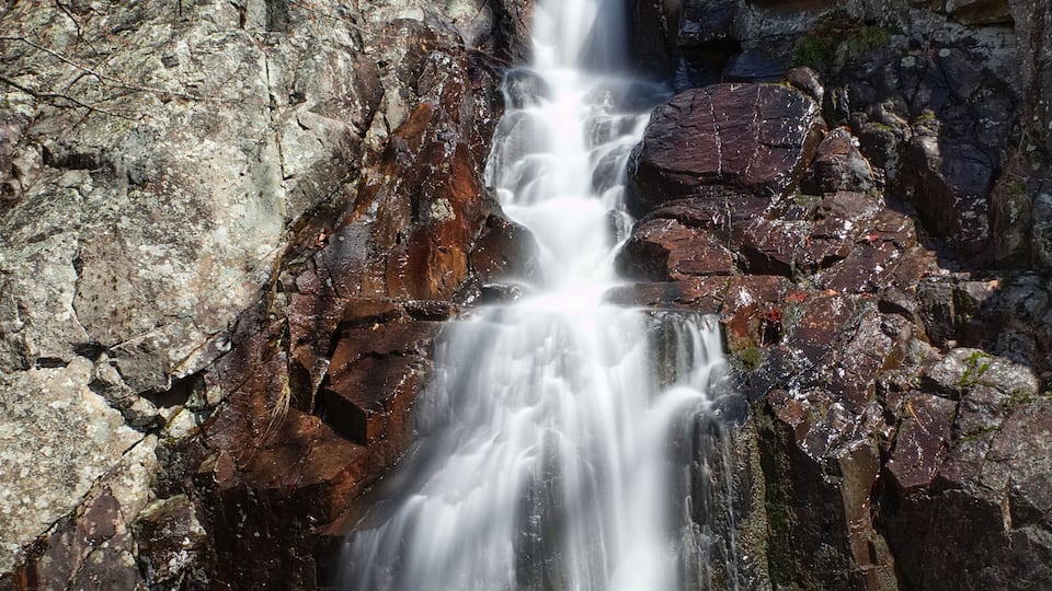 A waterfall cascading down a rocky cliff surrounded by trees.