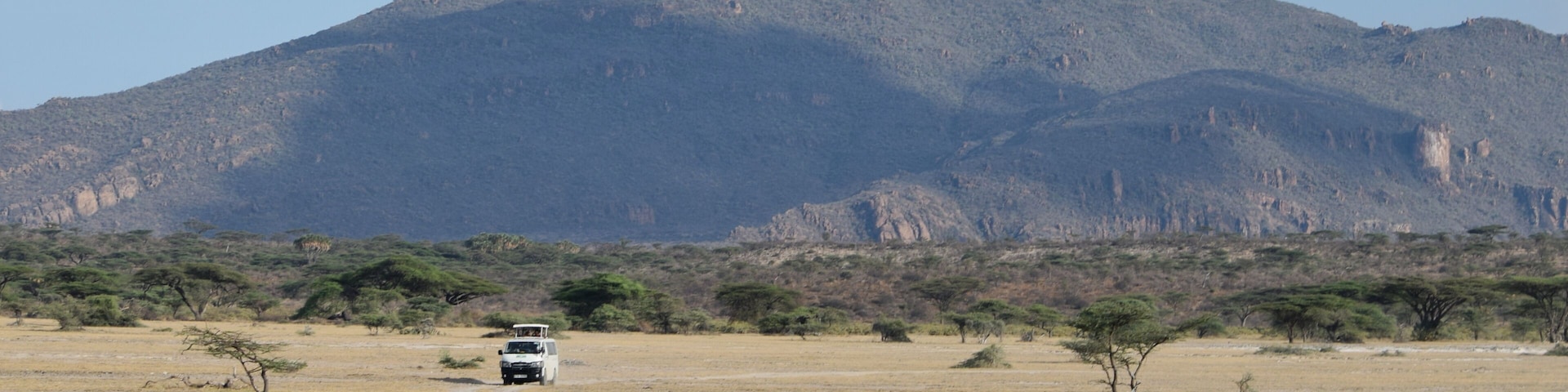 A tour van against a mountain background in the Shaba Game Reserve, Northern Kenya