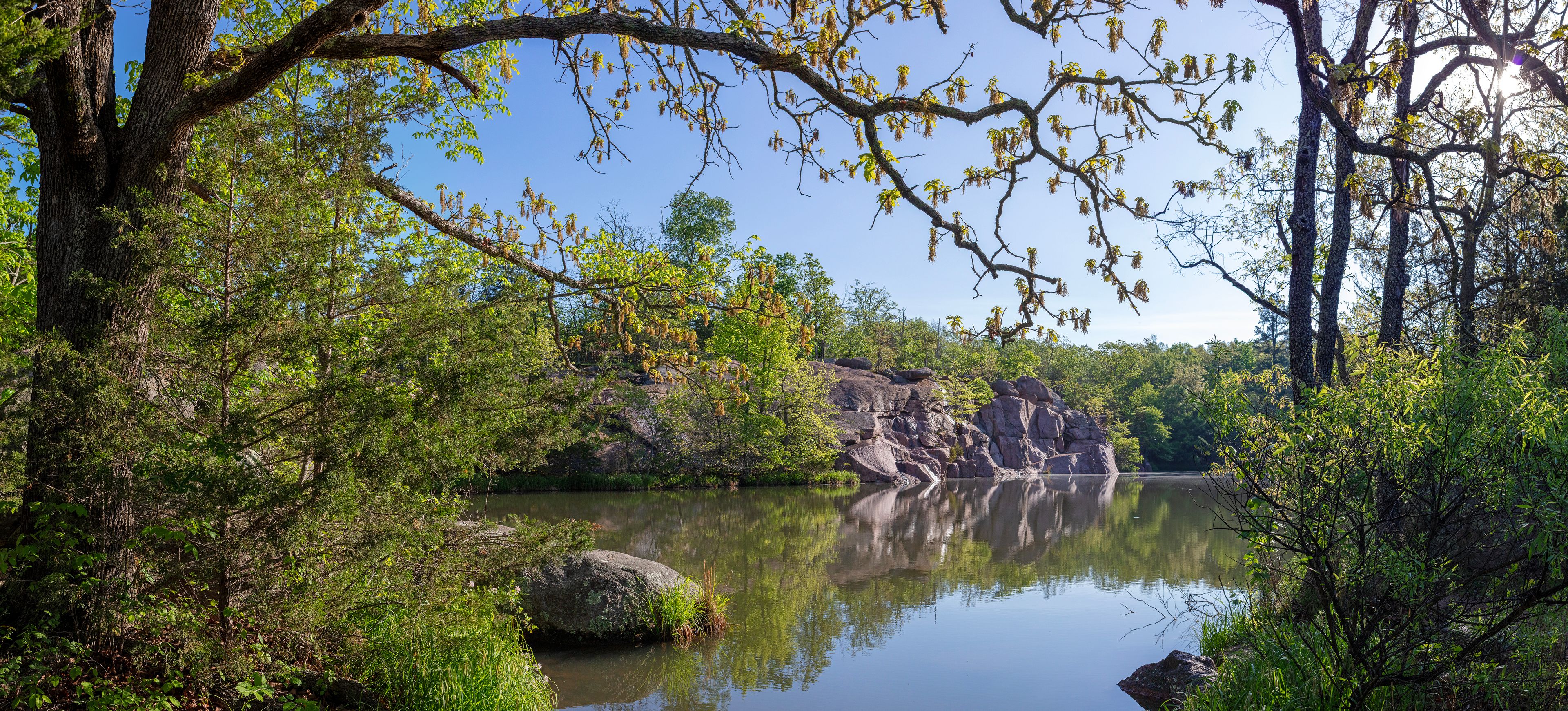 A calm river surrounded by dense foliage and rocky outcrops.