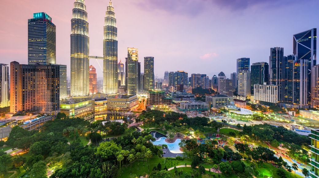 A cityscape with prominent skyscrapers, including the Petronas Towers, and a well-maintained park area.