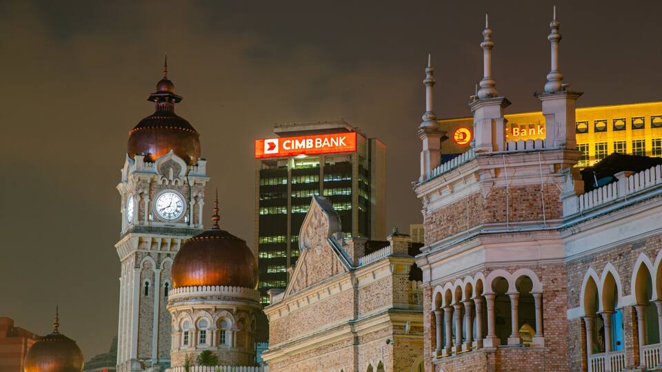 A historic clock tower, a modern skyscraper with a CMB Bank sign, and a traditional building with domes.