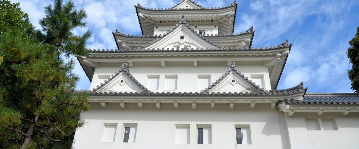 A traditional Japanese castle with multiple tiers, white walls, and a stone base.