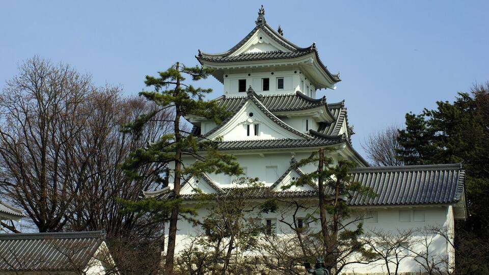 A traditional Japanese castle with multiple tiers and a white exterior.
