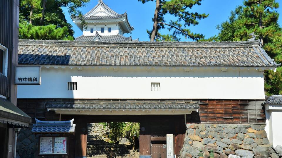 A traditional Japanese building with a tiled roof and wooden gate.