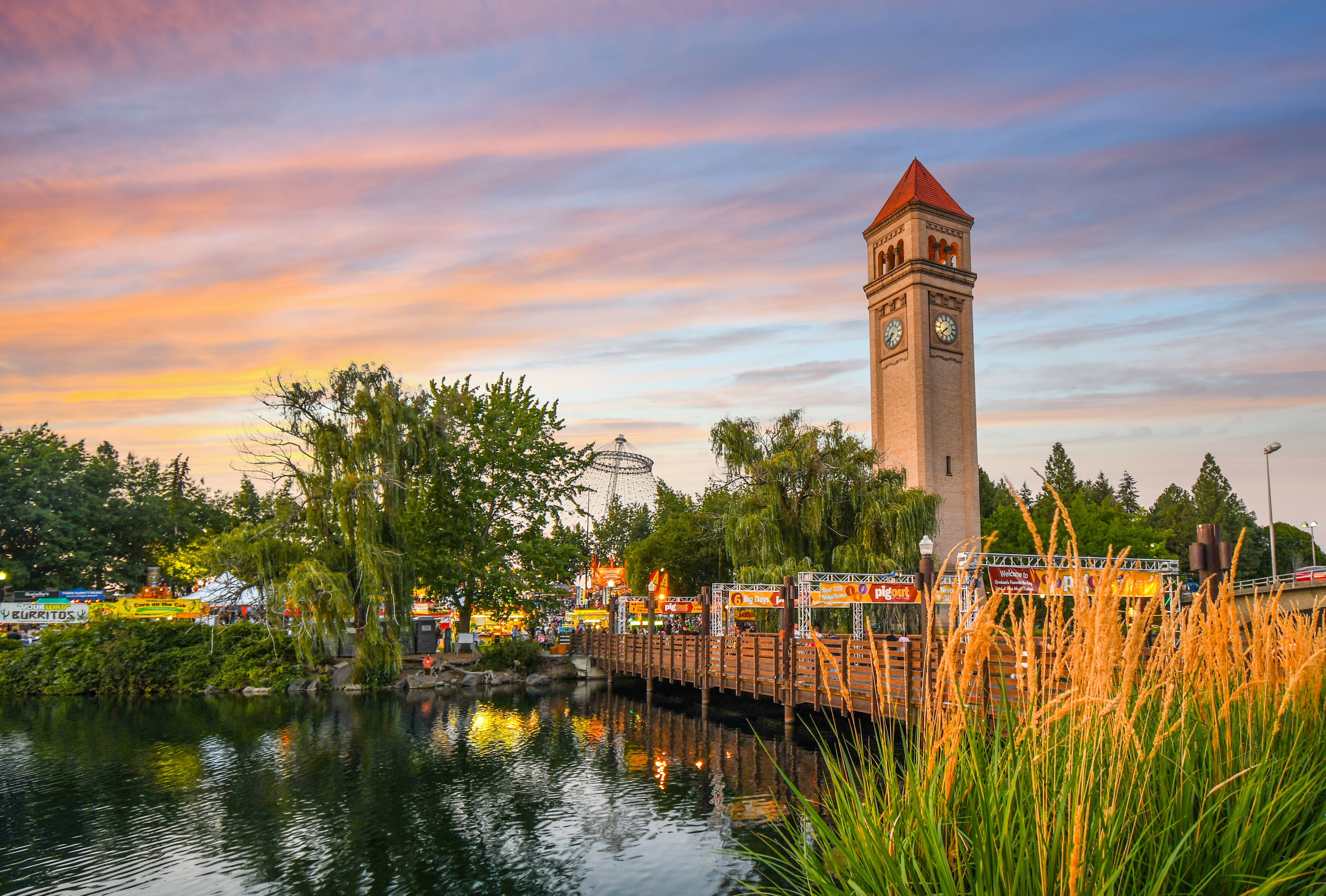 Festival goers enjoy a colorful sunset at the annual Pig out in the Park at Riverfront Park along the Spokane River in Spokane, Washington