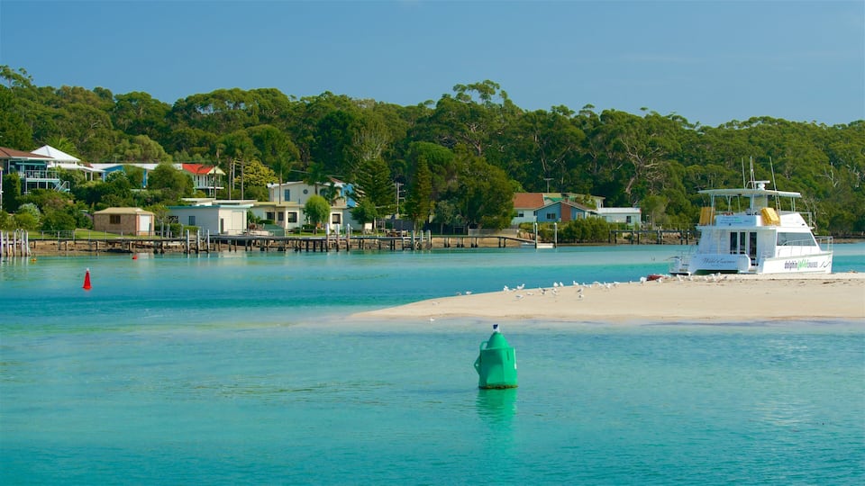 A coastal scene with a beach, a boat named 'Wild Escudo', and houses along the shore.