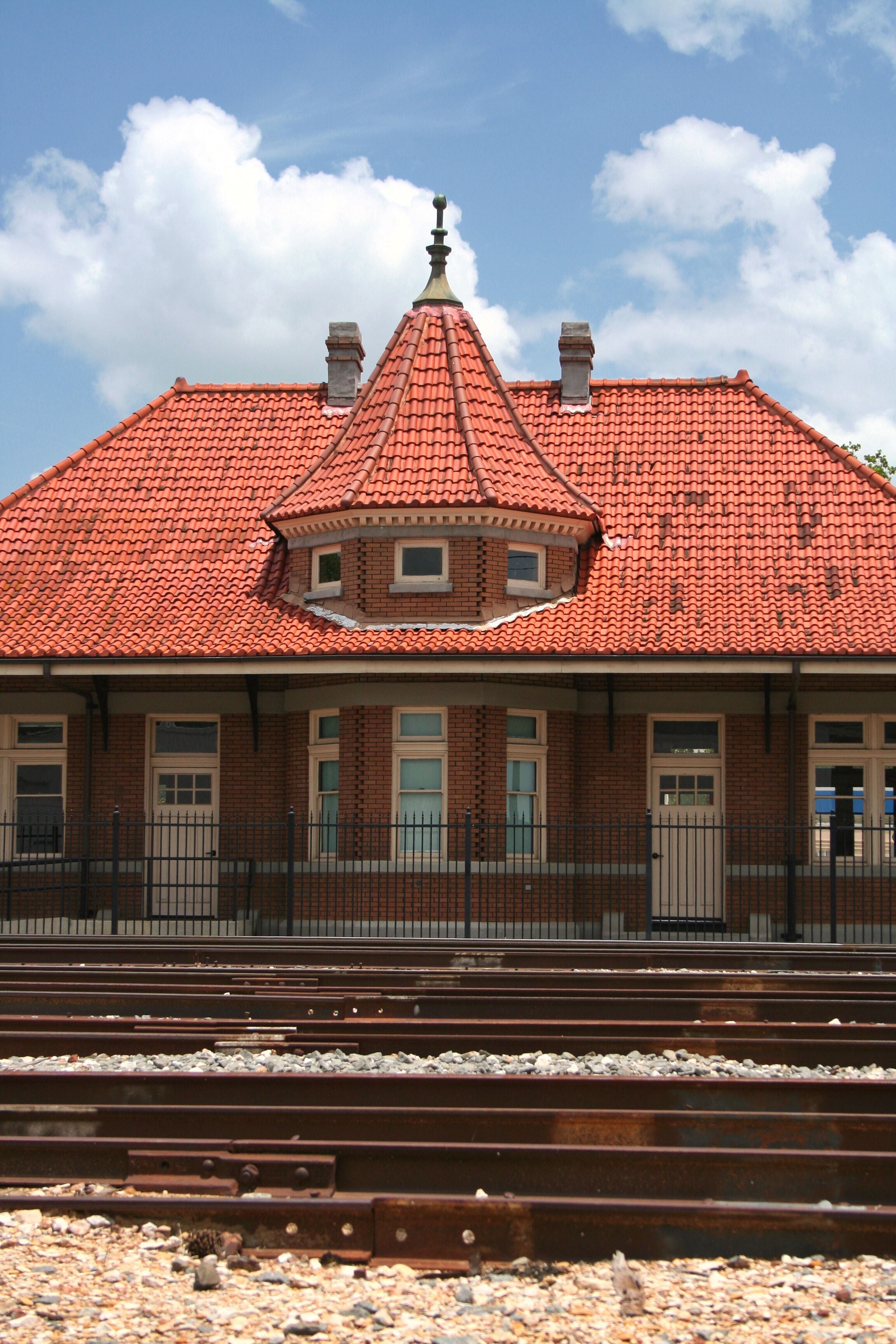 A building with a red-tiled roof, brick walls, and a central tower.