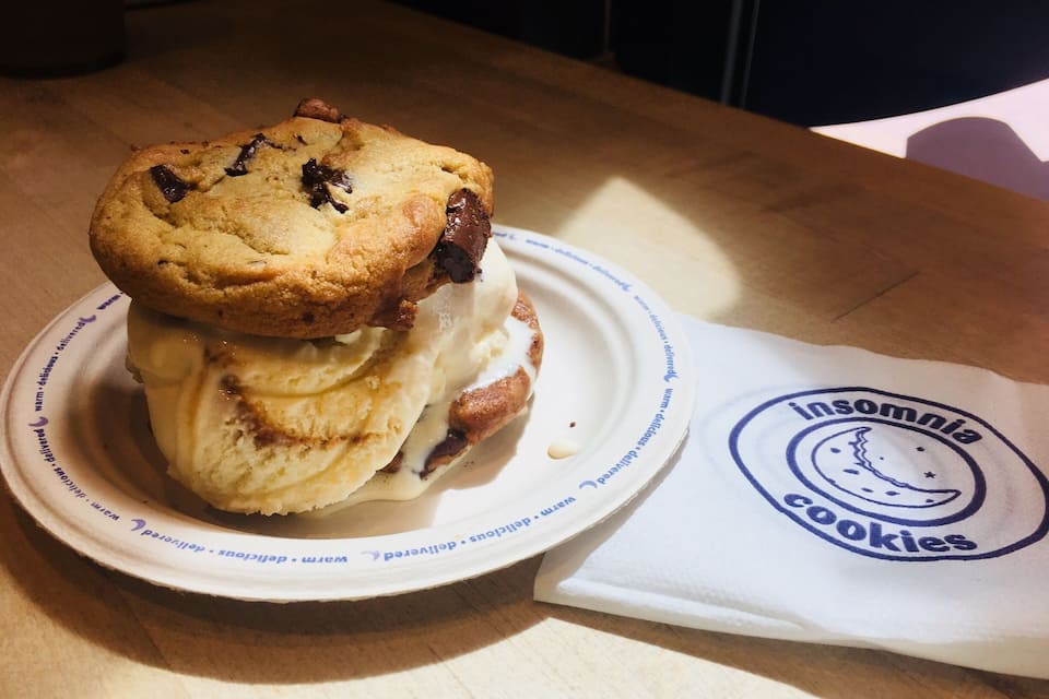 A cookie sandwich on a plate with a napkin beside it.
