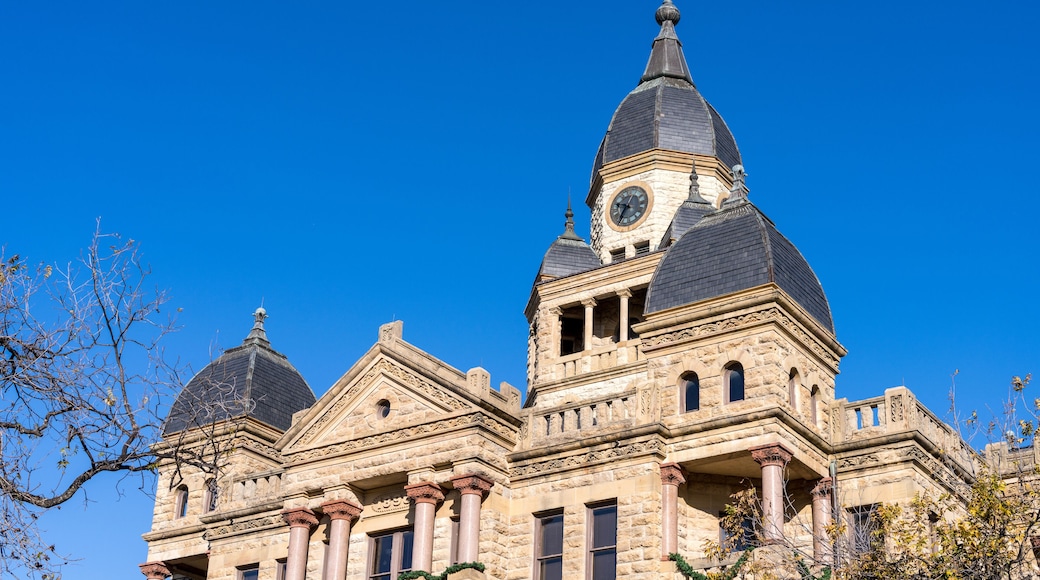 A historic building with a clock tower and dome under a clear blue sky.