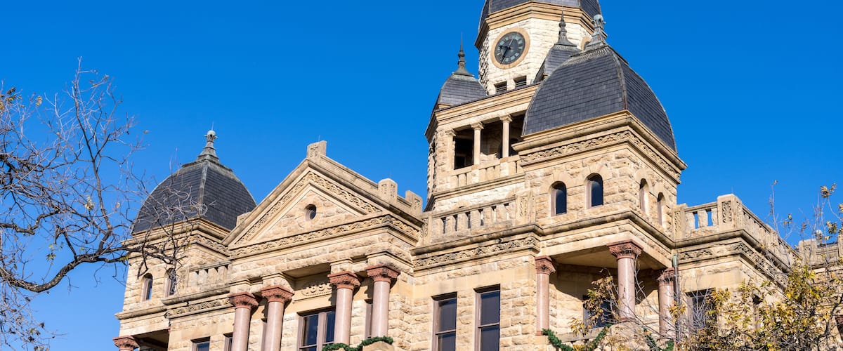 A historic building with a clock tower and dome under a clear blue sky.