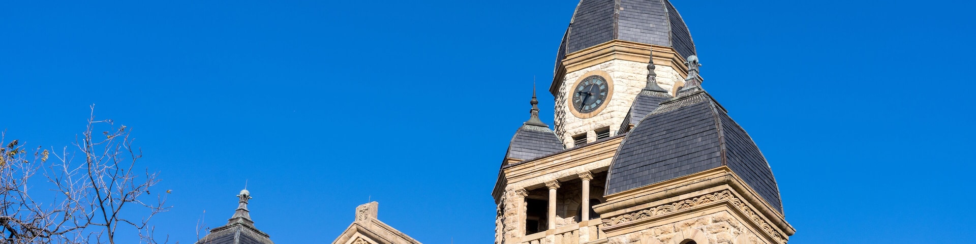 Um edifício histórico com torre do relógio e cúpula sob um céu azul límpido.