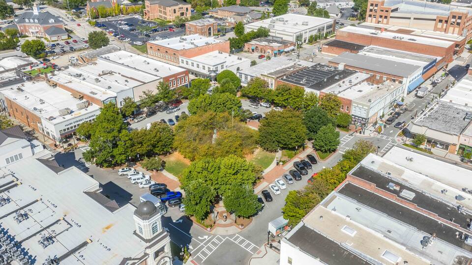 An aerial view of a town with a central green park surrounded by buildings and streets.