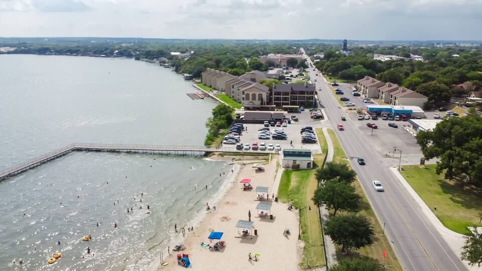 A coastal town with a pier, beach, and a road with cars.