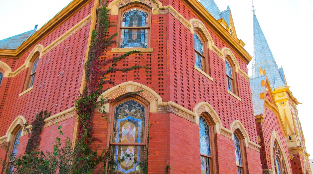 Beautiful church building in Greenville, TX, USA. Bright red brick wall of house with stained-glass windows and decor detail against blue sky.