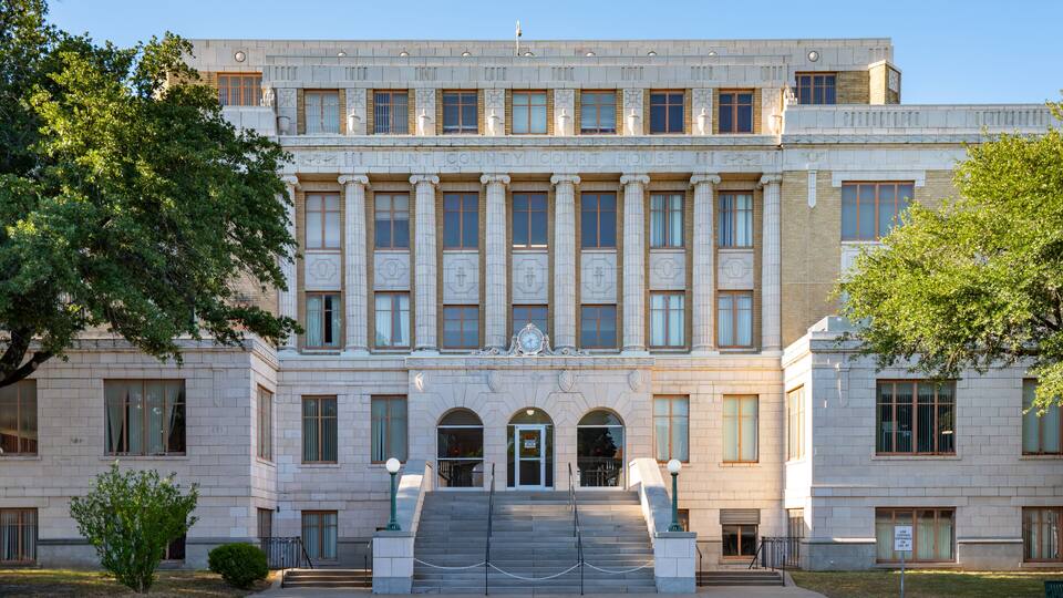 A large, historic courthouse with a grand entrance, columns, and a clock.