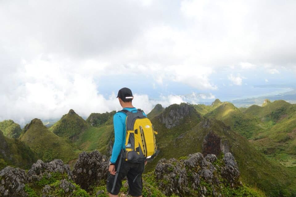 A hiker with a yellow backpack on a mountain ridge.