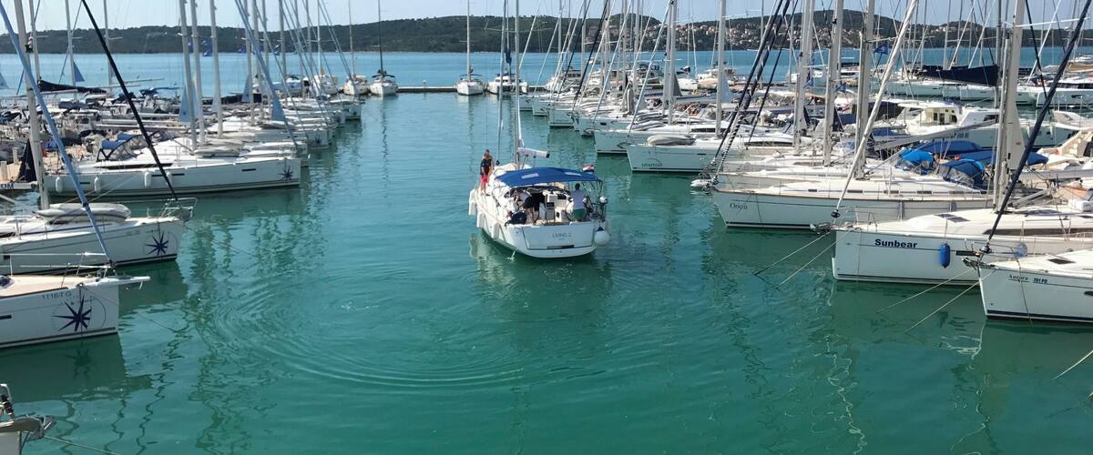 A marina with numerous sailboats docked in calm waters.