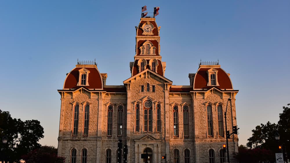 A large, historic building with a prominent clock tower, arched windows, and a symmetrical facade.