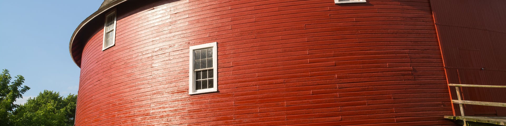 A red cylindrical building with a sloped roof and a small window.