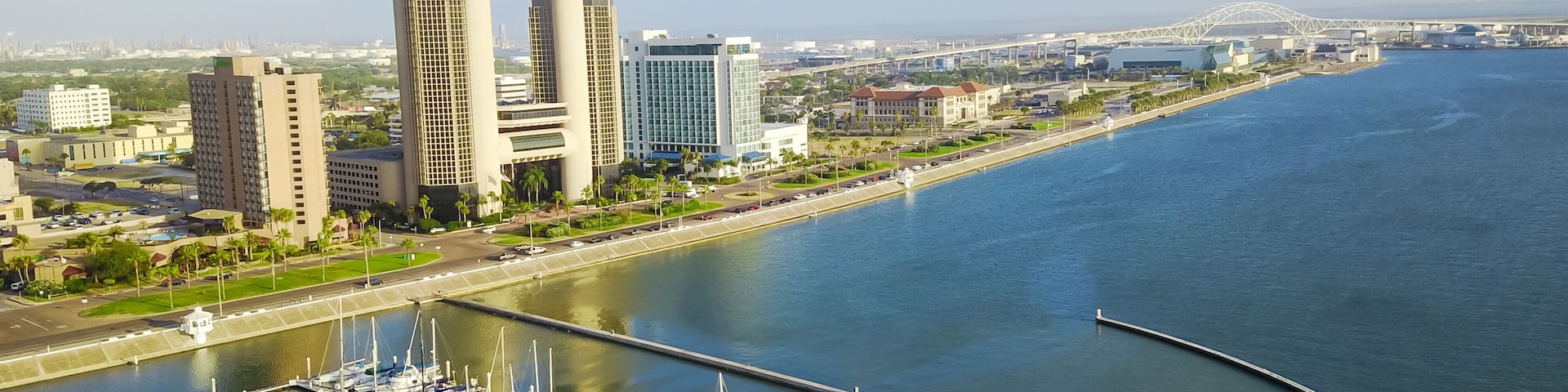 Panorama aerial view Bayfront area of Corpus Christi with skylines and marina piers row of boat, sailboat and yacht at sunrise. City harbor bridge far right in distance. A Texas city on Gulf of Mexico