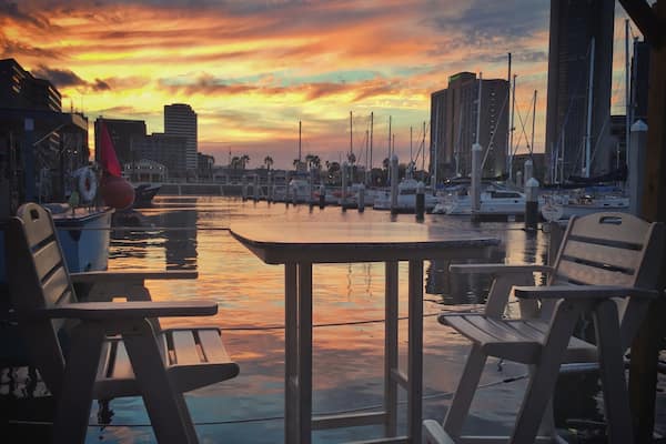 On a work-road trip to McAllen, Texas I had the opportunity to swing by Corpus Christi and grab dinner. No parading, no shopping planned, just a quick bite before seeing more freeway. I wasn't expecting to see very much.
Boy, was I surprised. We stopped for dinner just 4 miles off our route at Harrison's in Corpus Christi. We sat in the "floating" seating, a roped off dock with tables and chairs, and enjoyed some of the town's talented musicians singing homegrown versions of Sublime songs. The sun set with beautiful yellow and orange colored clouds reflected in the water and I was amazed no others were photographing this beautiful scene. Maybe indifferent, or maybe used to the beauty that is this town, and us the tourists making ourselves clearly known.
Thank you Corpus Christi for your beauty and your meal. I'm sorry our stay was rushed, we will definitely be back!