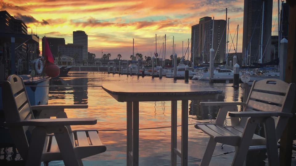 On a work-road trip to McAllen, Texas I had the opportunity to swing by Corpus Christi and grab dinner. No parading, no shopping planned, just a quick bite before seeing more freeway. I wasn't expecting to see very much.
Boy, was I surprised. We stopped for dinner just 4 miles off our route at Harrison's in Corpus Christi. We sat in the "floating" seating, a roped off dock with tables and chairs, and enjoyed some of the town's talented musicians singing homegrown versions of Sublime songs. The sun set with beautiful yellow and orange colored clouds reflected in the water and I was amazed no others were photographing this beautiful scene. Maybe indifferent, or maybe used to the beauty that is this town, and us the tourists making ourselves clearly known.
Thank you Corpus Christi for your beauty and your meal. I'm sorry our stay was rushed, we will definitely be back!