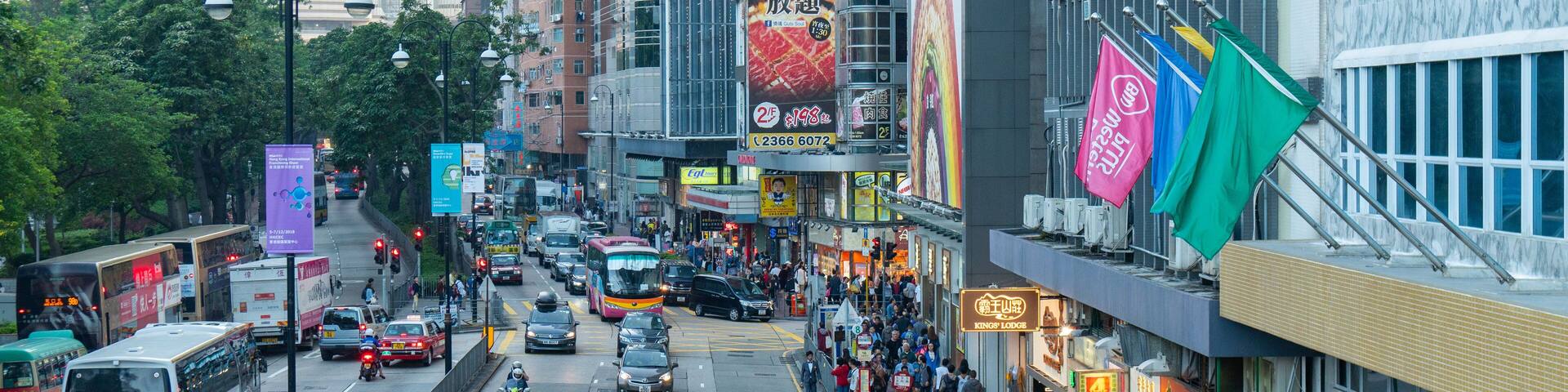 A busy urban street with buses, cars, and pedestrians.