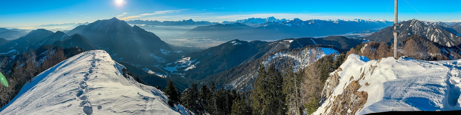 Majestic wooden cross of mountain peak Kobesnock in Gailtal Alps, Bleiberger Erzberg, Carinthia, Austria. Panoramic view of snow capped mountains of Julian Alps and Higher Tauern. Winter wonderland
