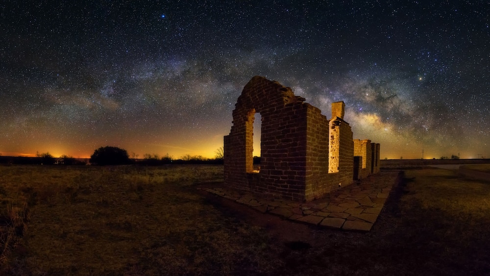 Les vestiges dâun ancien bĂątiment en briques, Ă©clairĂ©s par un ciel Ă©toilĂ© et la Voie lactĂ©e.