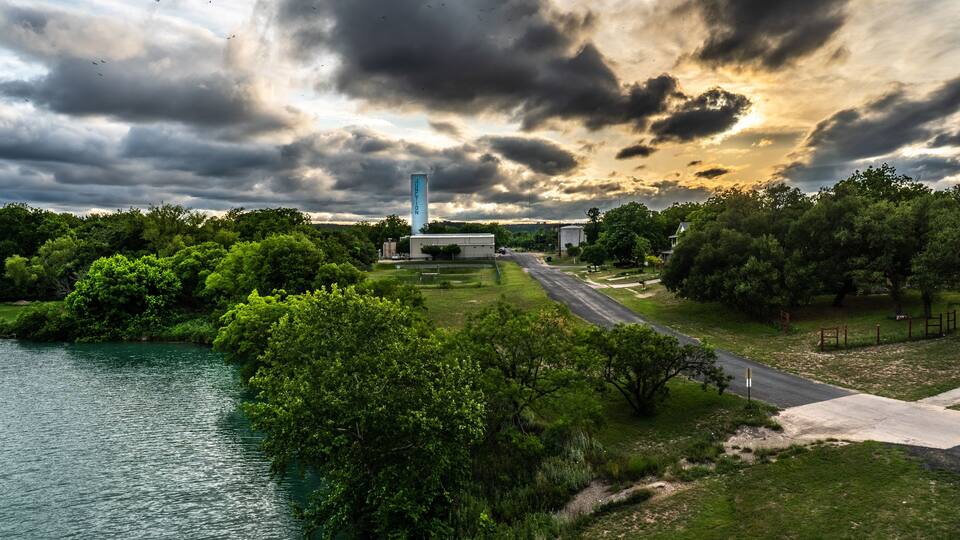 A river, green trees, a road, and a tall tower.