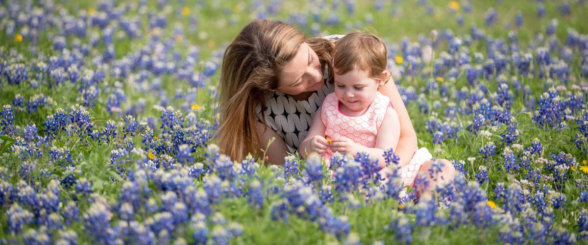 Una mujer y un niño en un campo de flores azules.