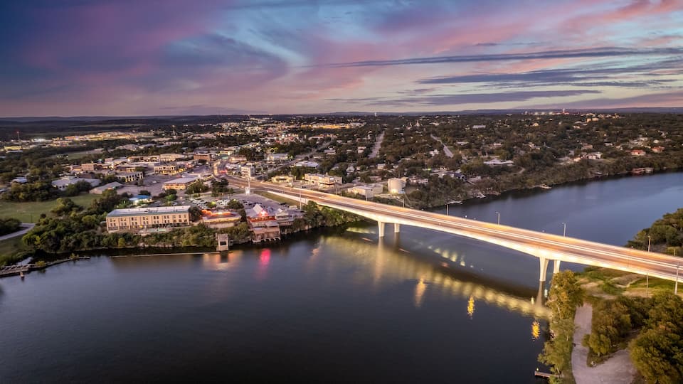 A river with a bridge, a town, and a large building with a dome.