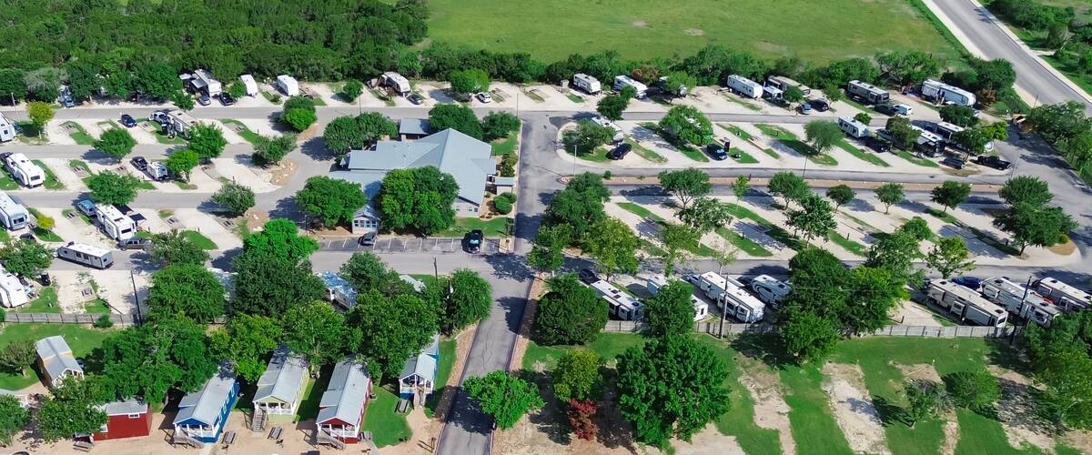An aerial view of a campground with RVs, mobile homes, and a main road.