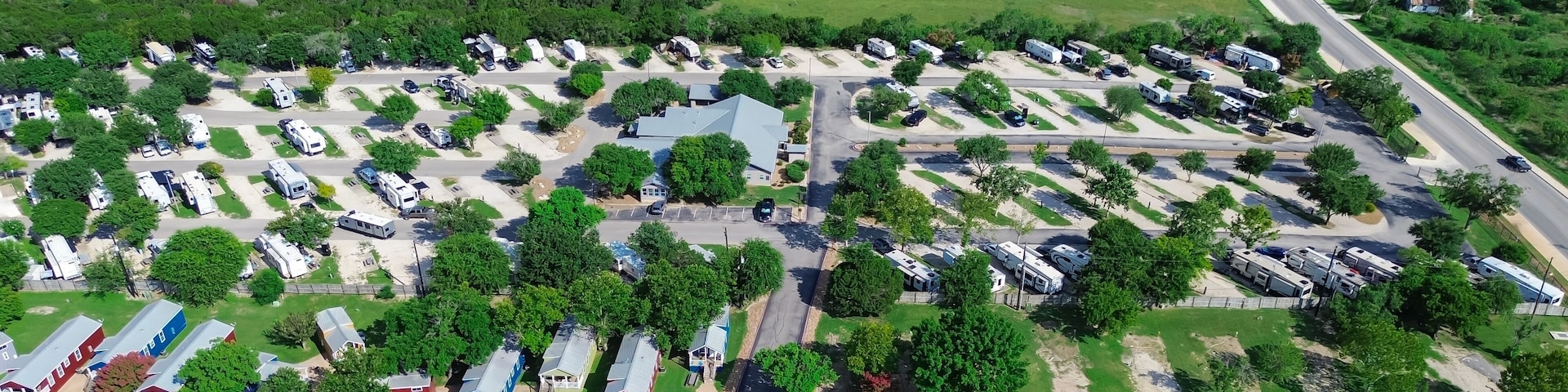 An aerial view of a campground with RVs, mobile homes, and a main road.