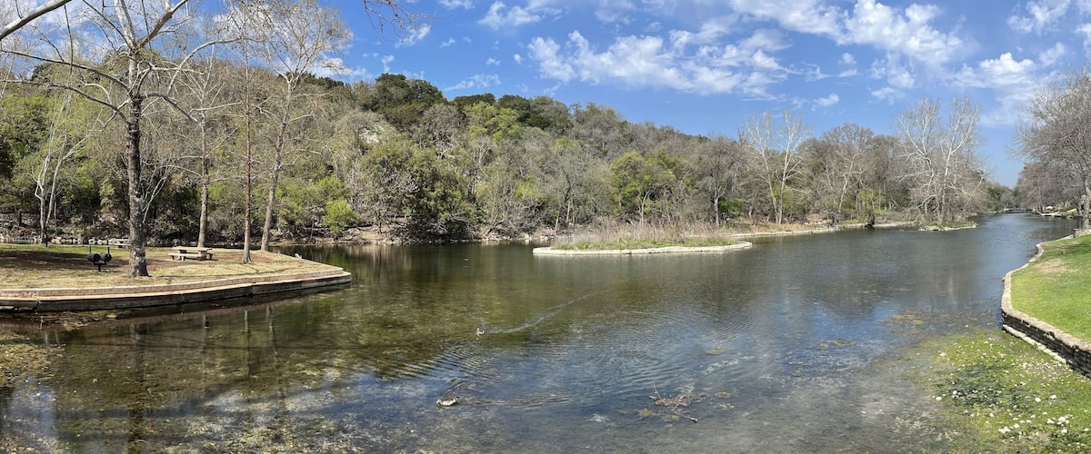 Un río de aguas cristalinas, rodeado de árboles y zonas verdes.