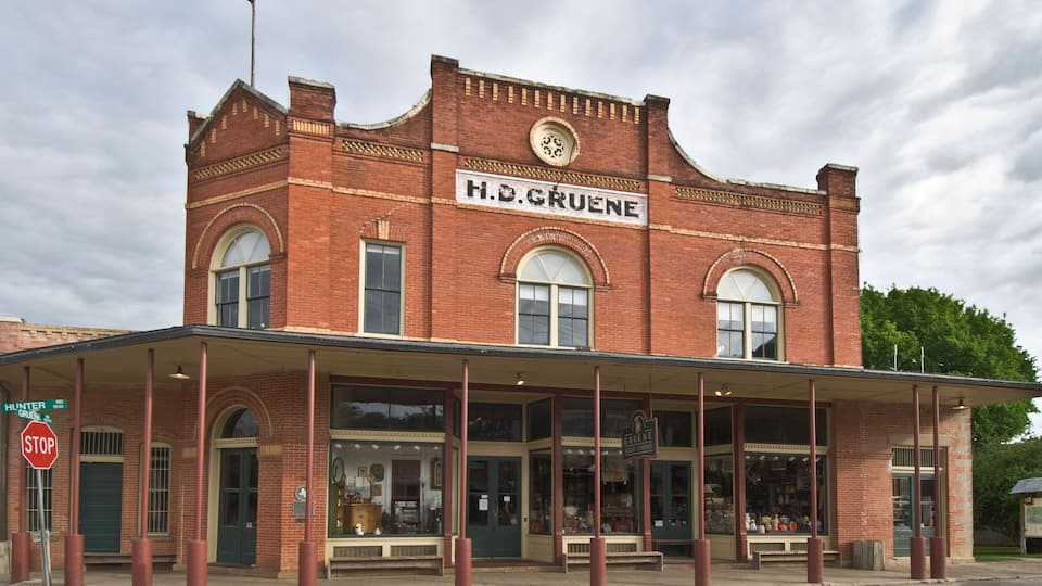 A historic H.D. Gruene building with a prominent sign, a covered front porch, and a stop sign at the entrance.