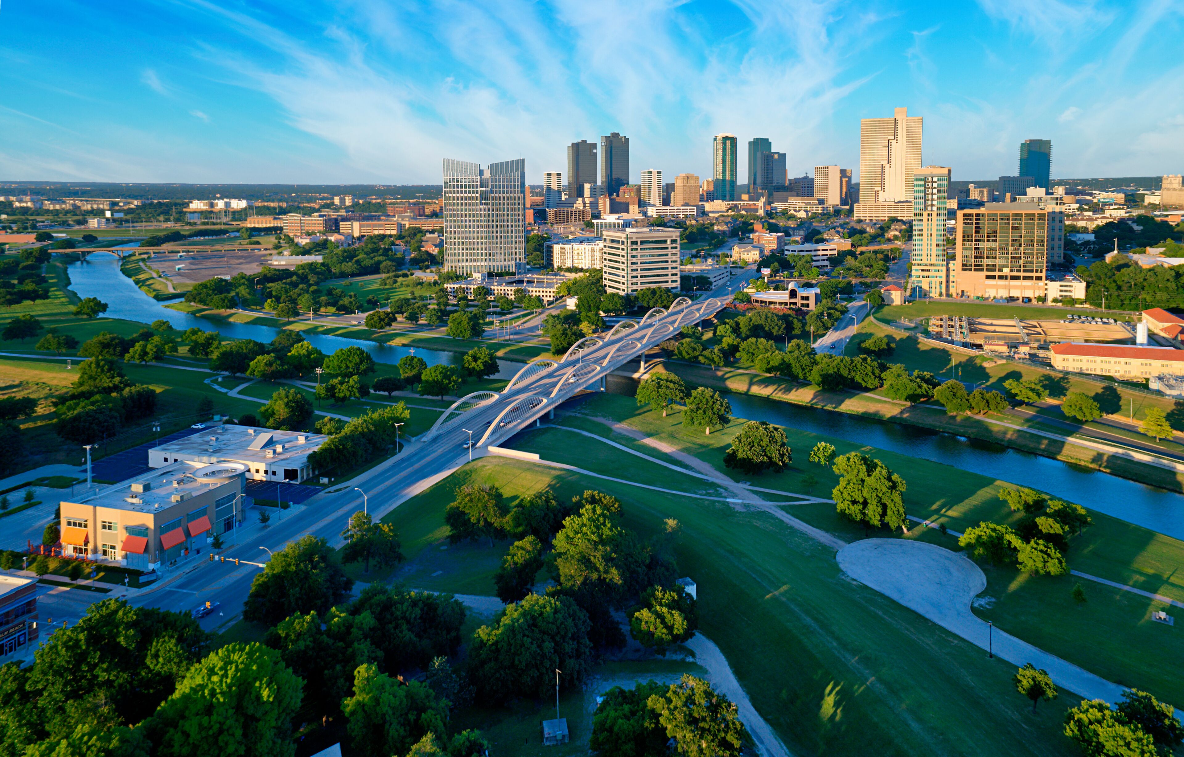 A cityscape with a river, green spaces, and modern buildings.