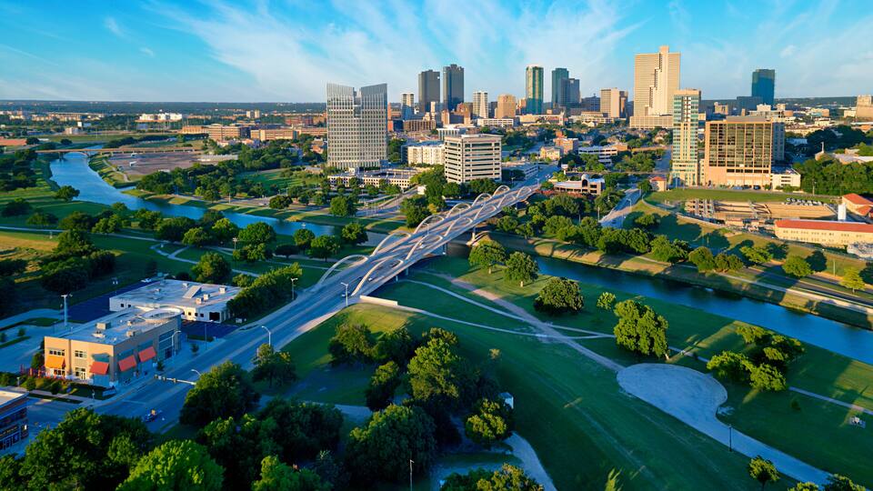 A cityscape with a river, green spaces, and modern buildings.