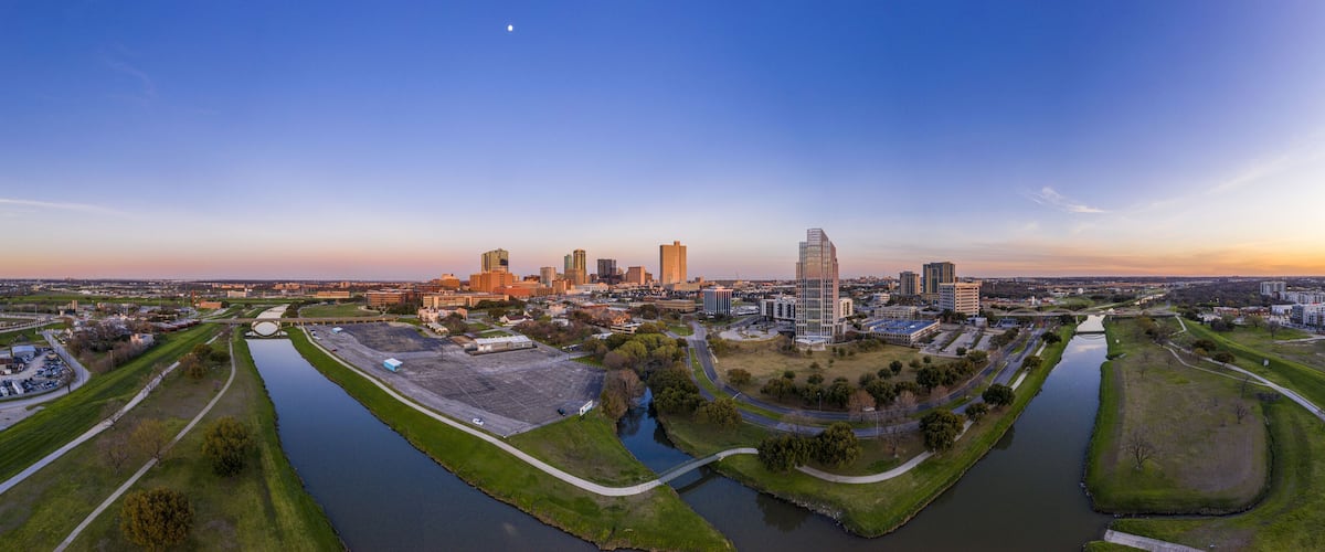 A cityscape with a river, green spaces, and various buildings.