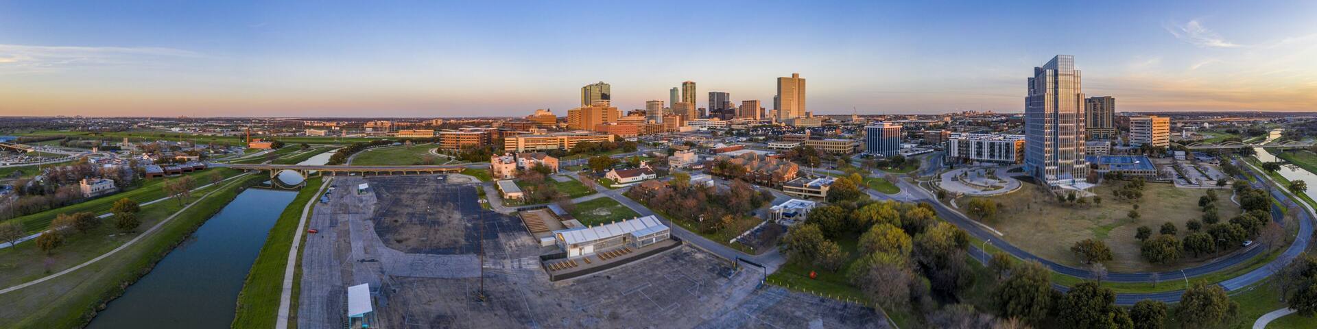 A city skyline with modern buildings, a river, and a large open construction site.