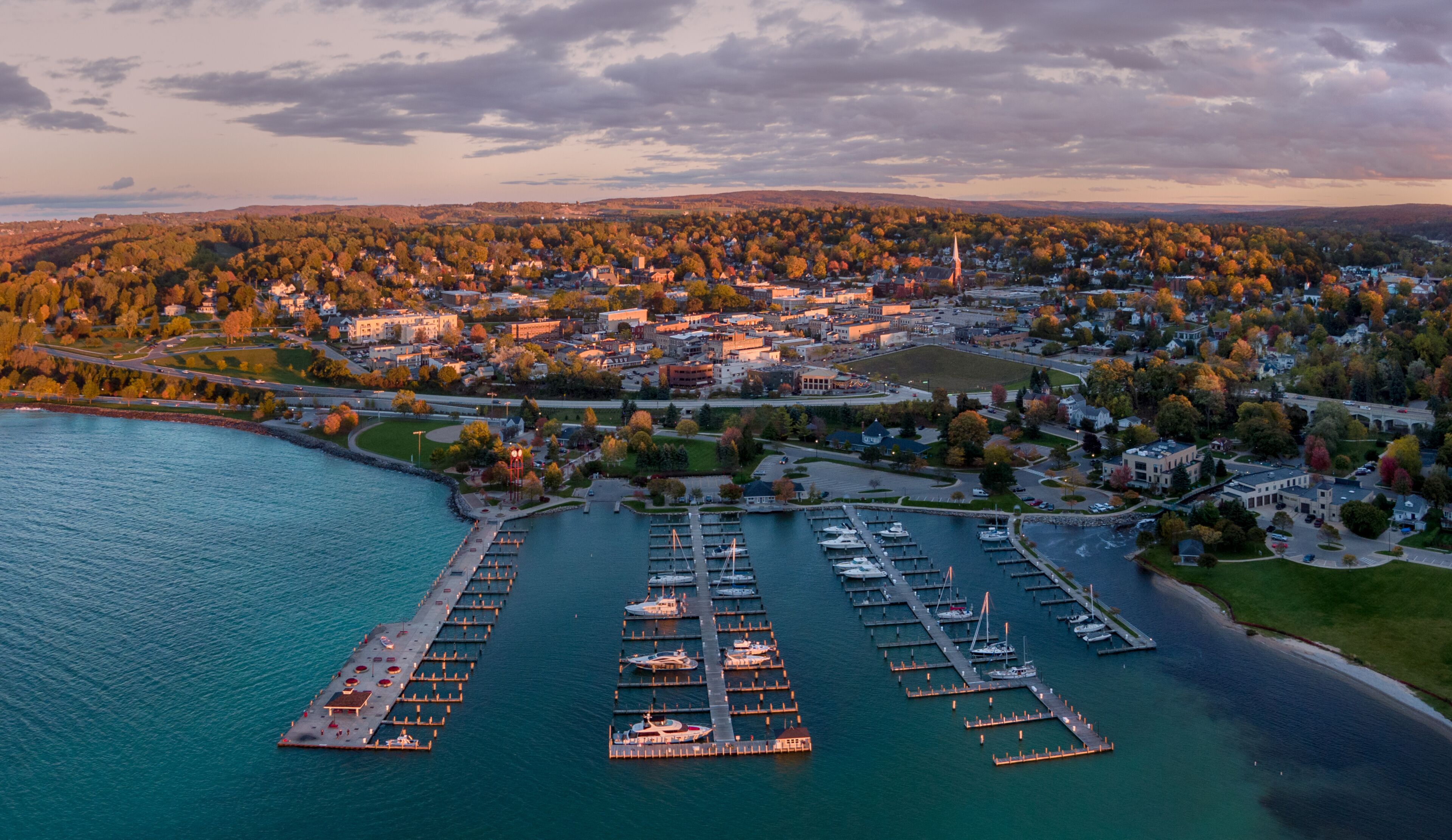 A coastal town with a marina, waterfront homes, and a prominent church spire.