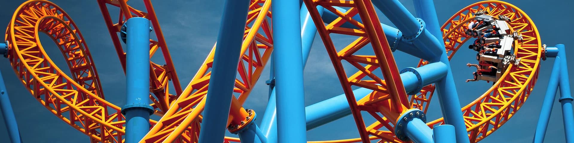 A roller coaster with blue and orange tracks against a clear sky.