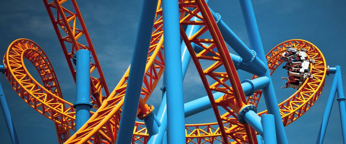 A roller coaster with blue and orange tracks against a clear sky.